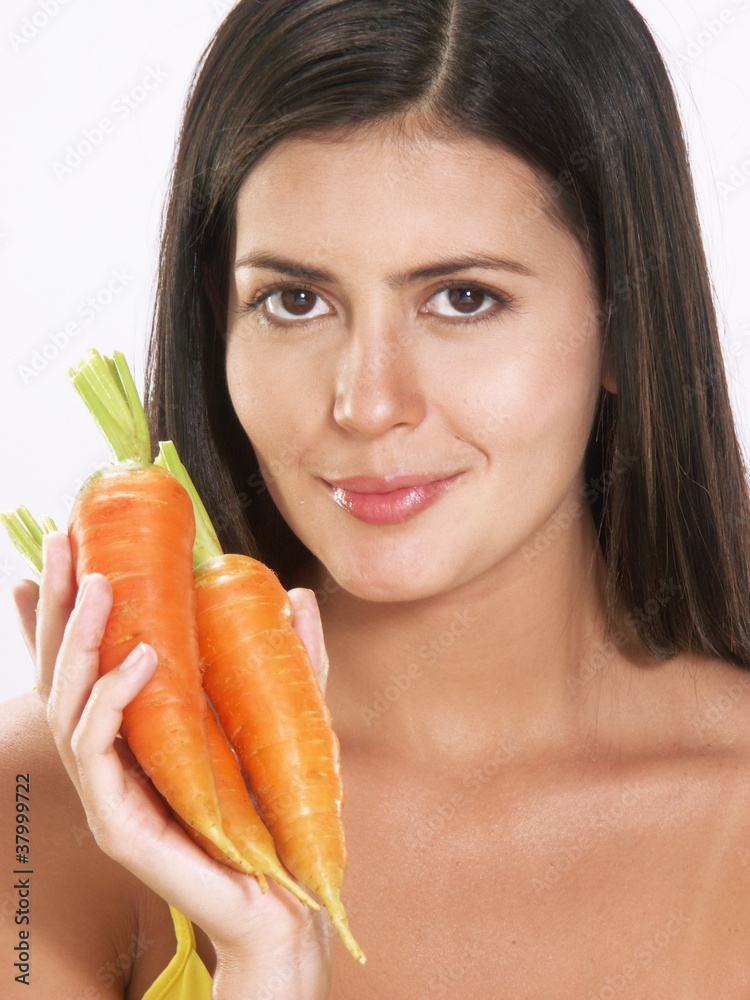 Joven mujer hispana sujetando zanahorias. Joven mujer hispana sujetando zanahorias.
