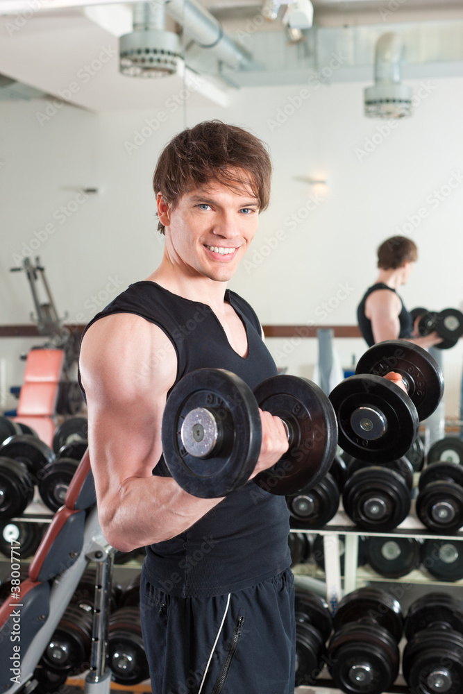 Sport - Mann trainiert mit Hanteln im Fitnessstudio Sport - Mann trainiert mit Hanteln im Fitnessstudio