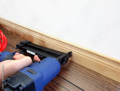 Fotografija Male hand with carpenter tool installing baseboard