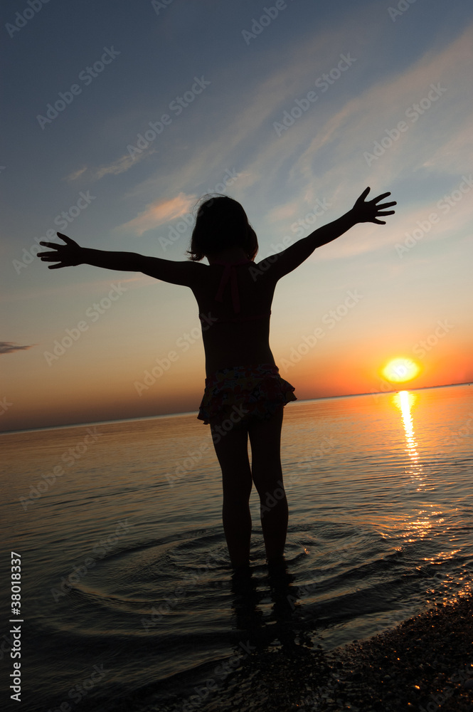 Child silhouette on sunset beach. Kid on summer vacation