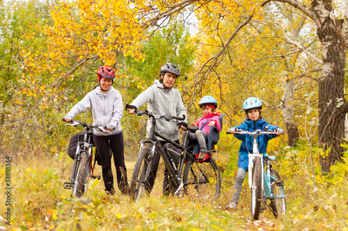Happy family cycling outdoors, parents with kids on bikes