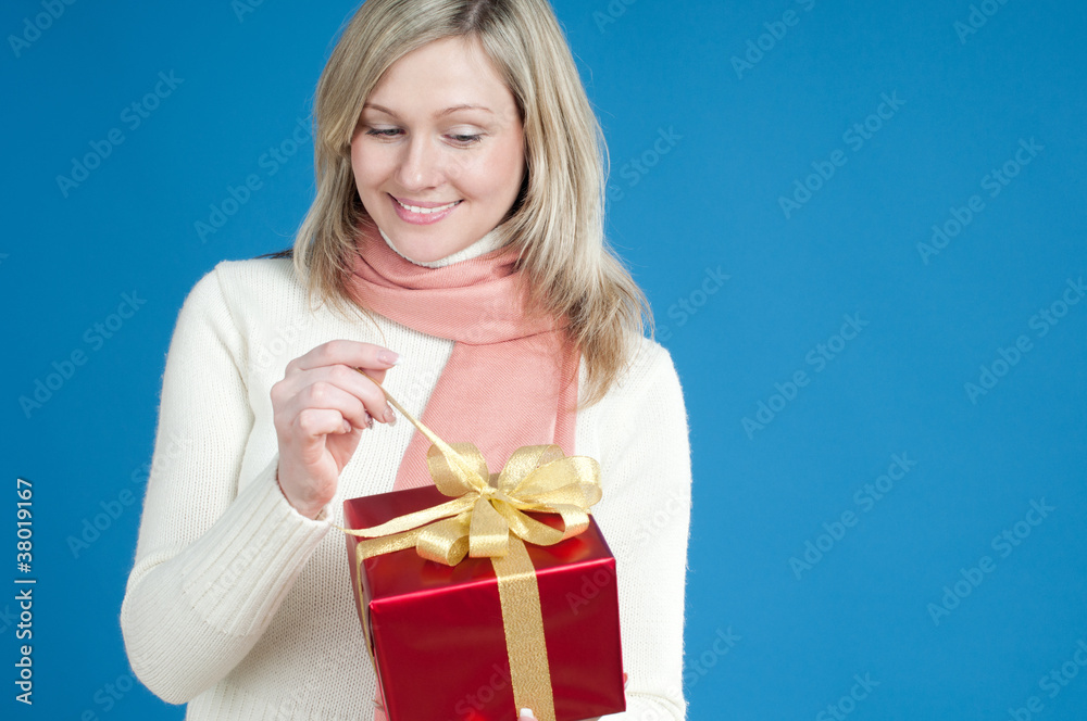 Happy blond woman opening red gift box, over blue background Happy blond woman opening red gift box, over blue background