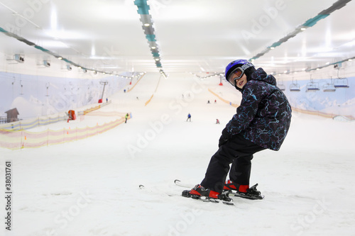 Happy child dressed in sports clothes and helmet and ski goggles photo