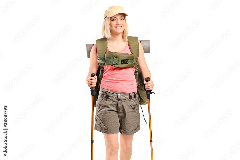 A smiling woman with backpack and hiking poles posing