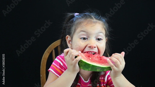 Young girl eating watermelon and spitting out seed photo