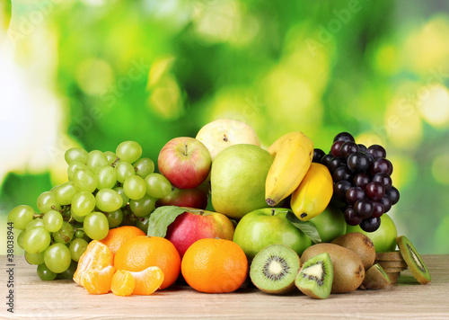 Fototapeta Naklejka Na Ścianę i Meble -  Ripe juicy fruits on wooden table on green background