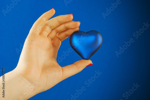 Hand holds a heart shaped gift against blue background