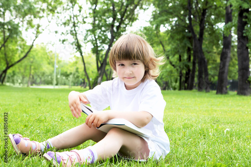 Portrait of little girl reading a book in the park