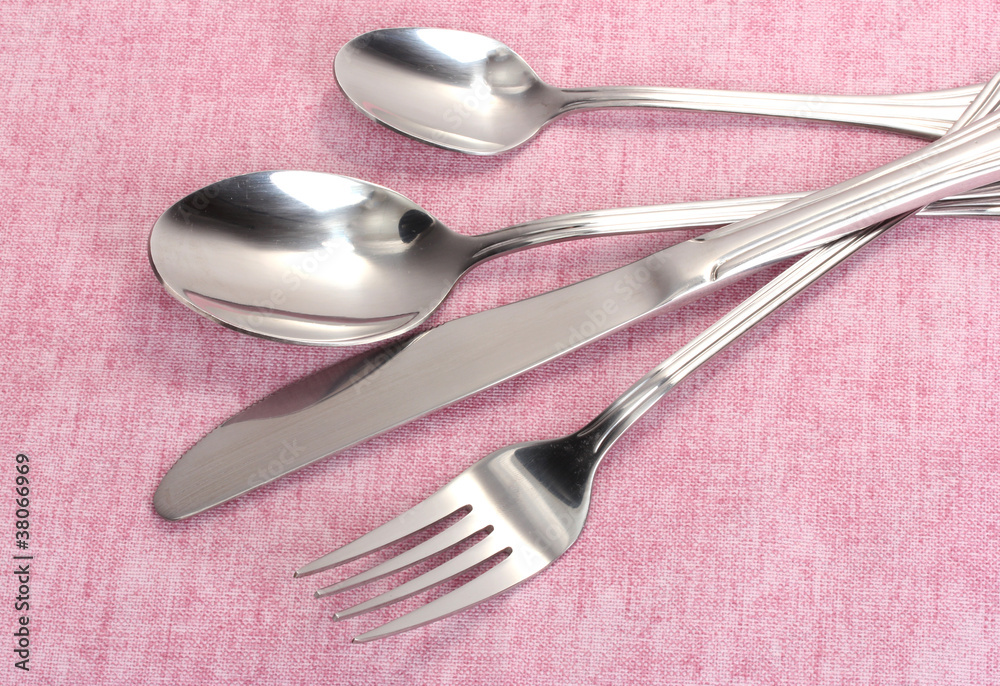 Fork, spoon and knife on a pink tablecloth Fork, spoon and knife on a pink tablecloth