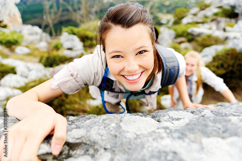 Hiker smiles while climbing up a rocky wall