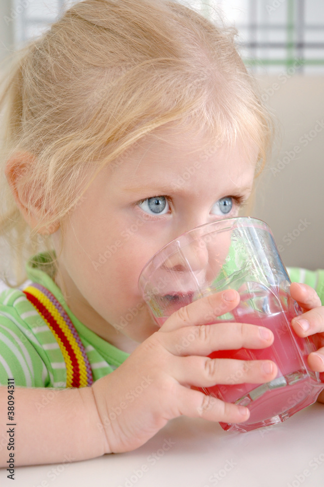 The little girl drinks a pink drink from a glass The little girl drinks a pink drink from a glass