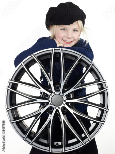Obraz na płótnie Cute blonde girl with knit cap leans over an aloy wheel