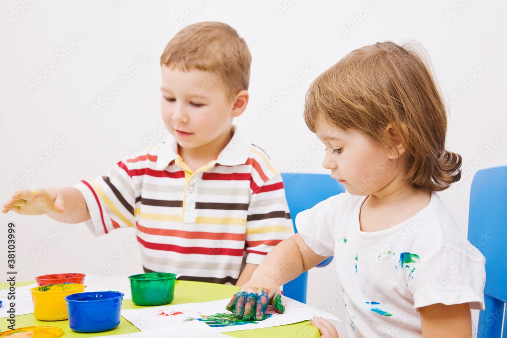 Boy and girl paint colors sitting at the table Boy and girl paint colors sitting at the table