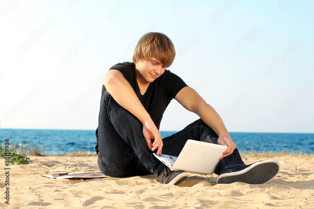 Young student man using laptop on the beach