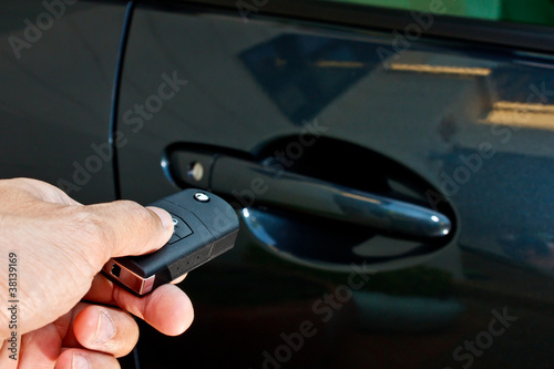 a hand holding a remote control pointing to a car
