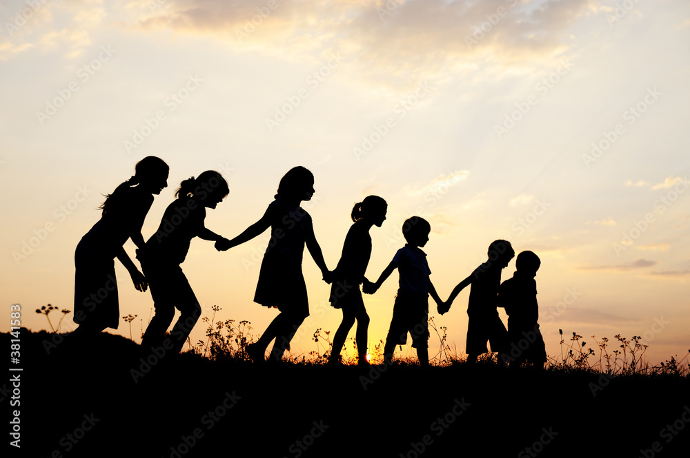 Silhouette, group of happy children playing on meadow,