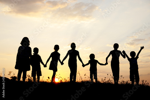 Silhouette, group of happy children playing on meadow