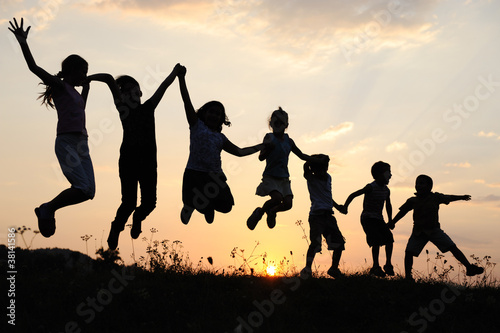 Silhouette, group of happy children playing on meadow,