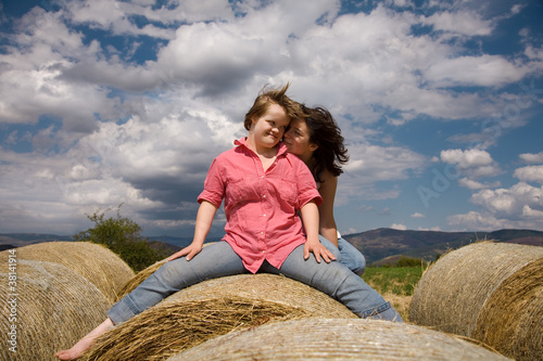 Sisters seated on a straw bale.