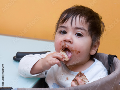 bambino che mangia cialda con cioccolato a tavola