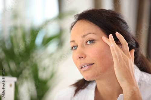 a woman spreading out cosmetic cream on her face