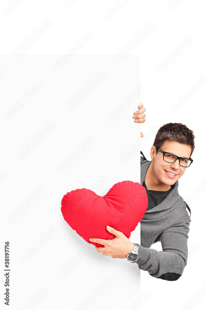 Young male holding a red heart shaped pillow and a blank banner Young male holding a red heart shaped pillow and a blank banner