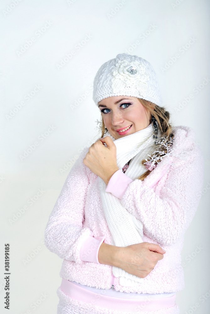 The young beautiful girl in a white cap and a scarf on a white b The young beautiful girl in a white cap and a scarf on a white b