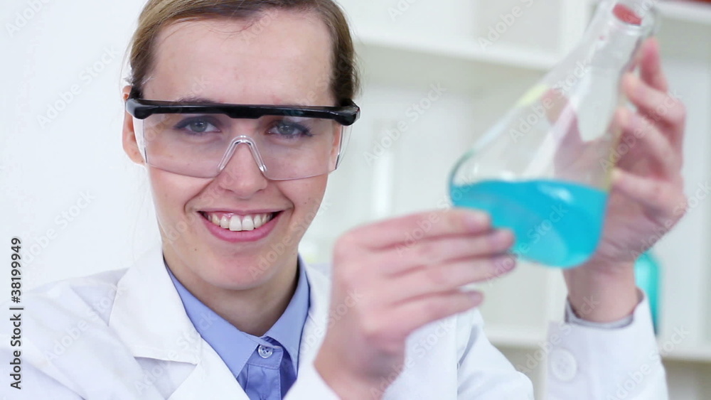 scientist mixing erlenmeyer flask with chemicals and smiling scientist mixing erlenmeyer flask with chemicals and smiling