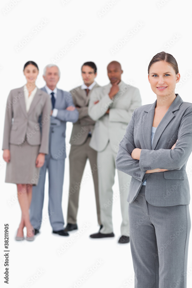 Saleswoman with arms folded and her team behind her Saleswoman with arms folded and her team behind her