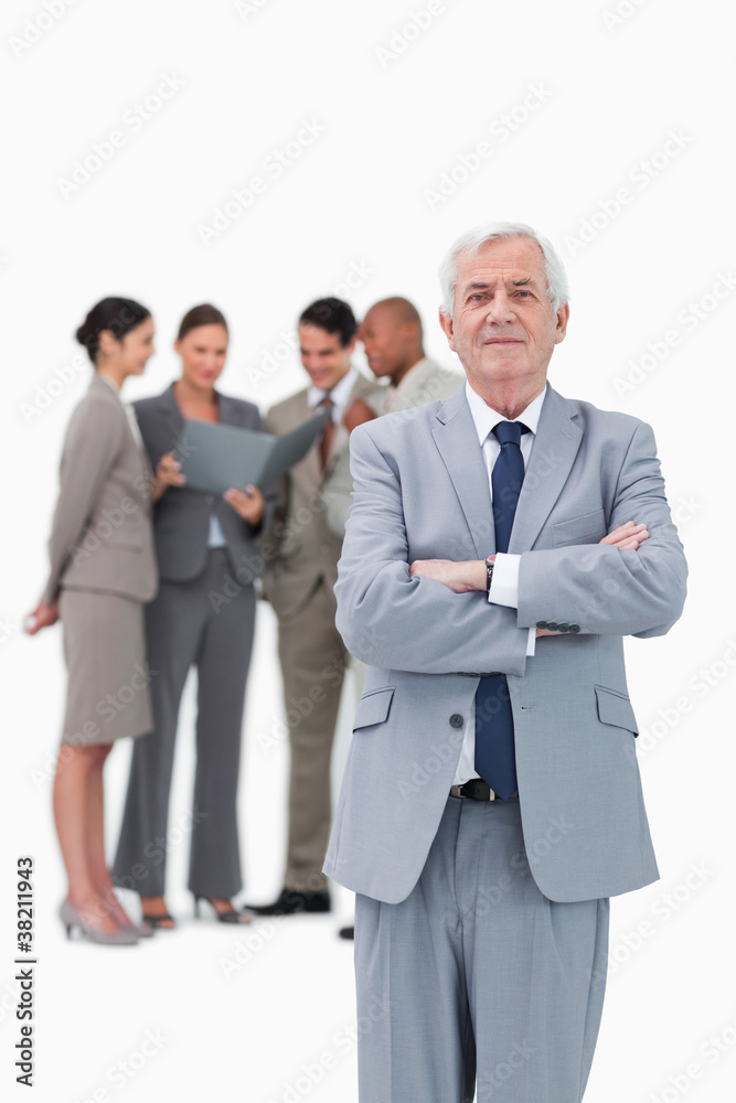 Mature businessman with arms folded and team behind him Mature businessman with arms folded and team behind him