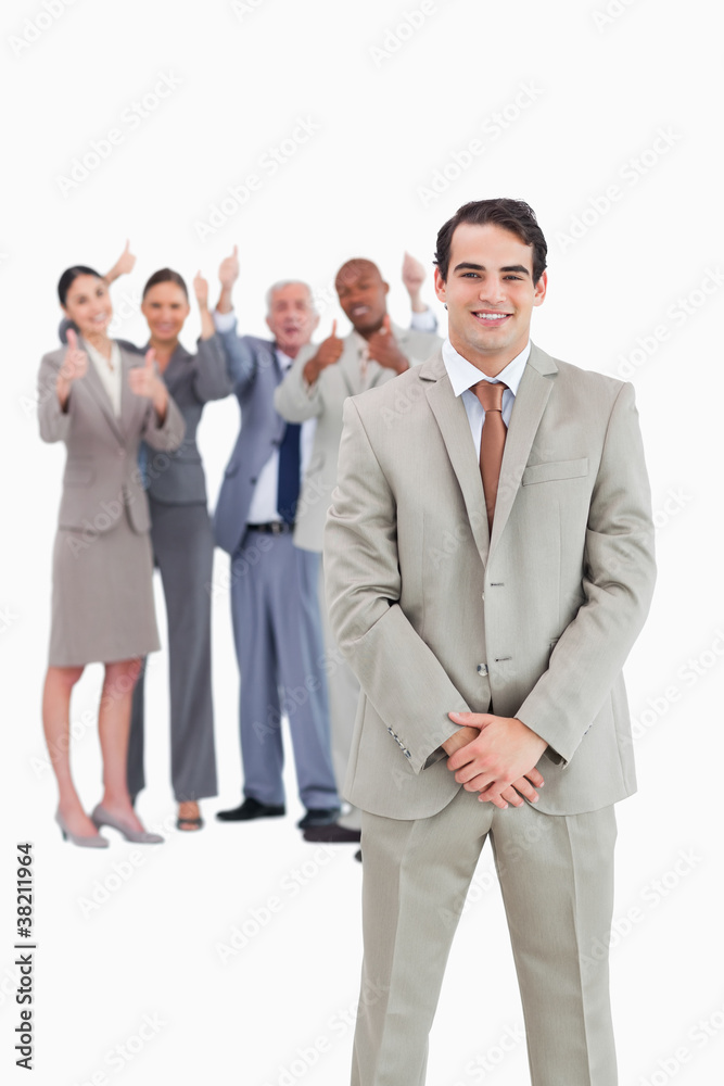 Smiling businessman with cheering team behind him Smiling businessman with cheering team behind him
