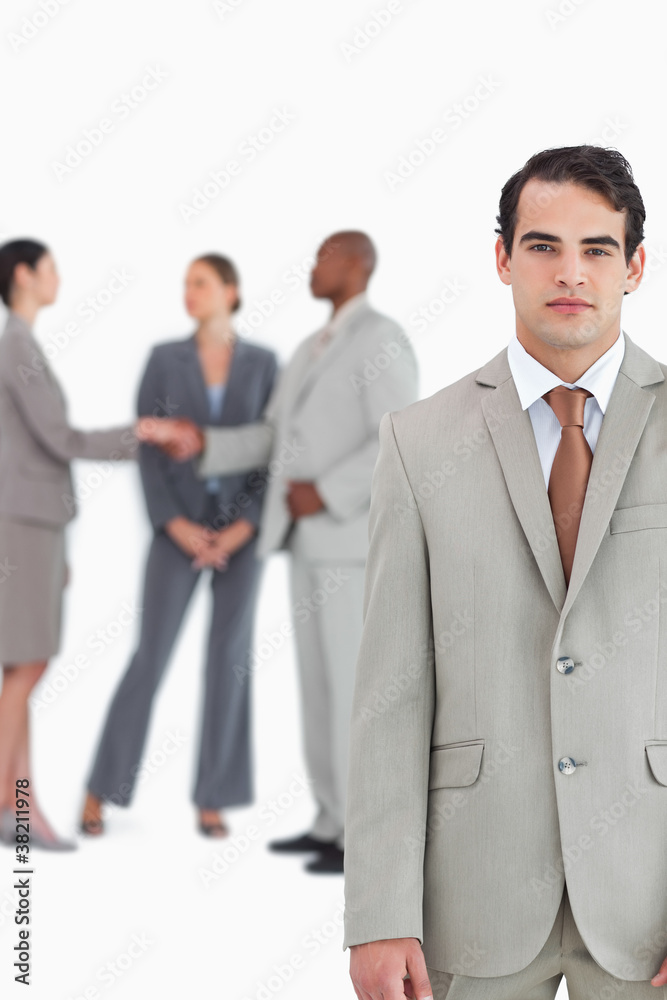 Serious salesman with businesspeople behind him Serious salesman with businesspeople behind him