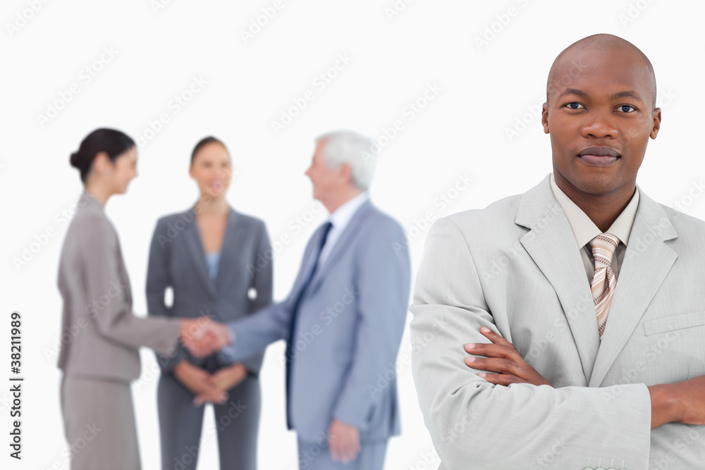 Businessman with arms folded and trading partners behind him Businessman with arms folded and trading partners behind him