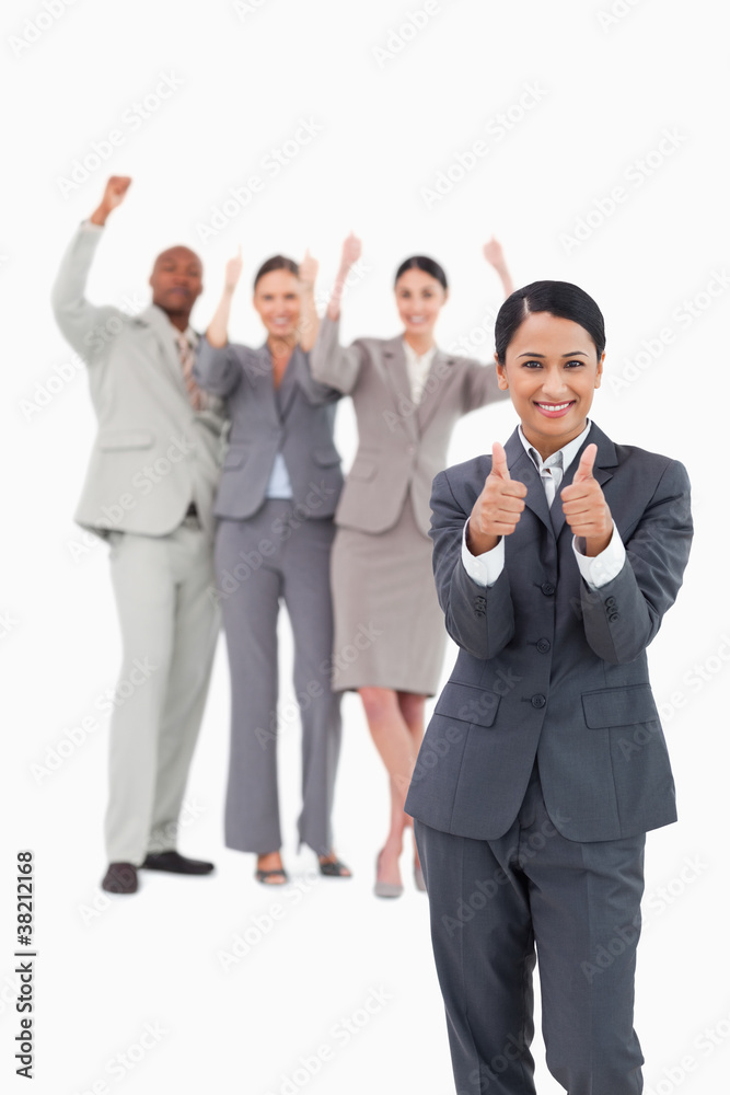 Saleswoman with cheering team behind her giving thumbs up Saleswoman with cheering team behind her giving thumbs up