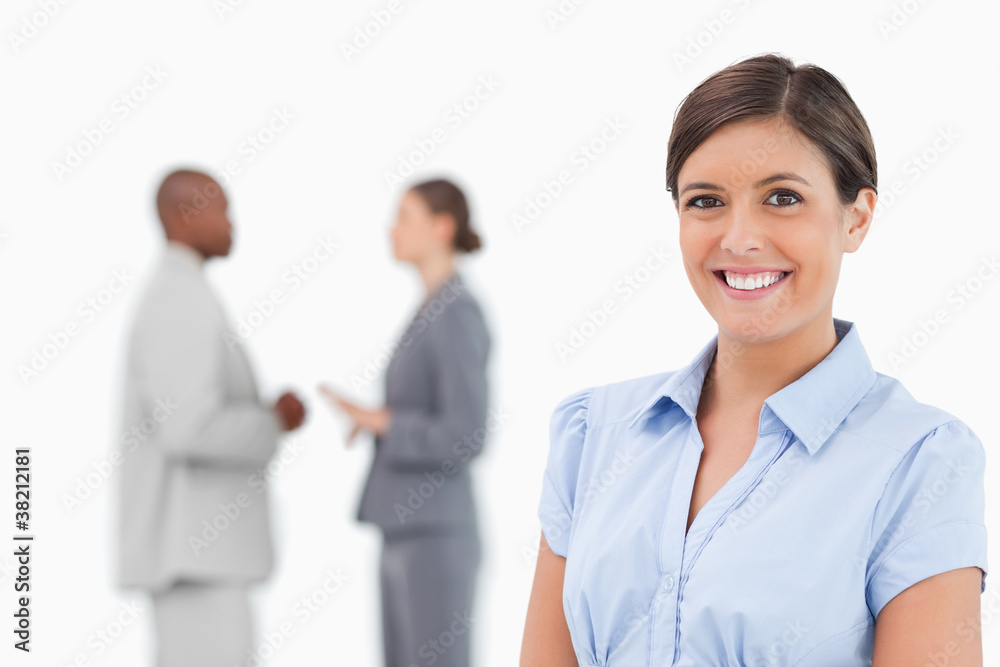 Smiling businesswoman with talking associates behind her Smiling businesswoman with talking associates behind her