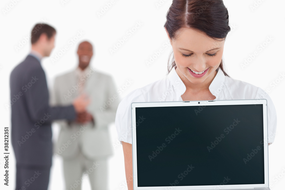Businesswoman showing laptop with associates behind her Businesswoman showing laptop with associates behind her