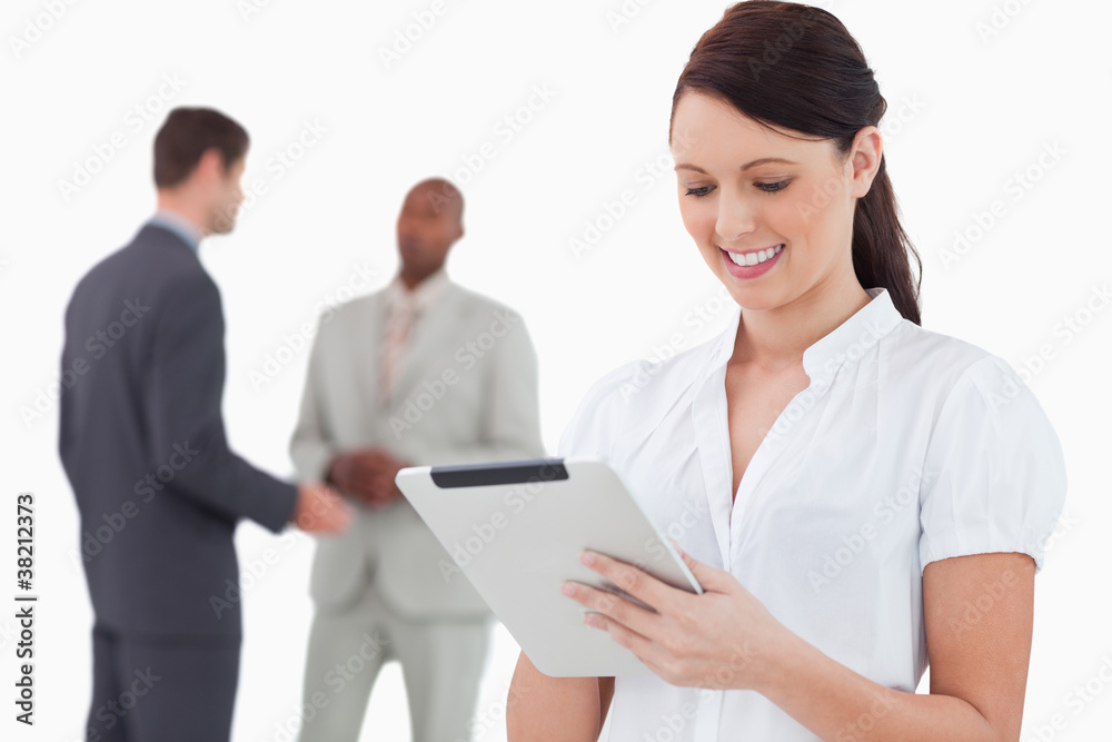 Saleswoman with tablet and colleagues behind her Saleswoman with tablet and colleagues behind her