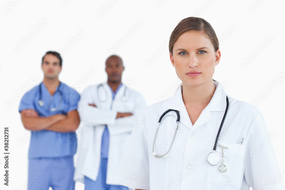Female doctor with male colleagues behind her Female doctor with male colleagues behind her