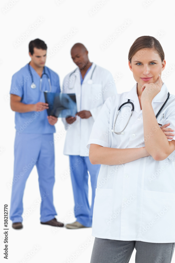 Thinking doctor with colleagues behind her Thinking doctor with colleagues behind her