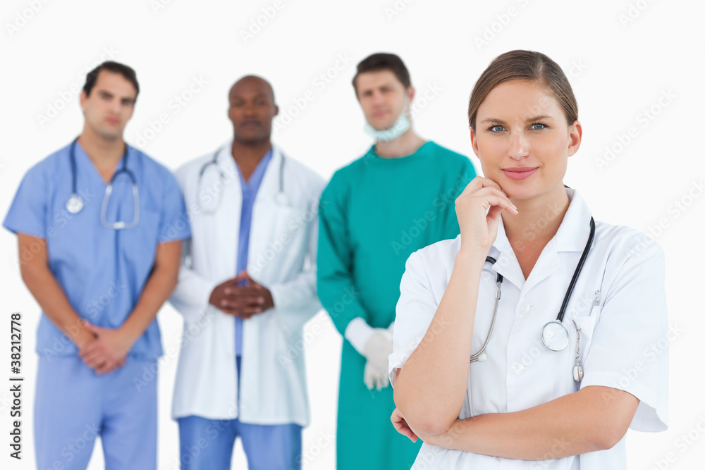 Thoughtful doctor with male colleagues behind her Thoughtful doctor with male colleagues behind her