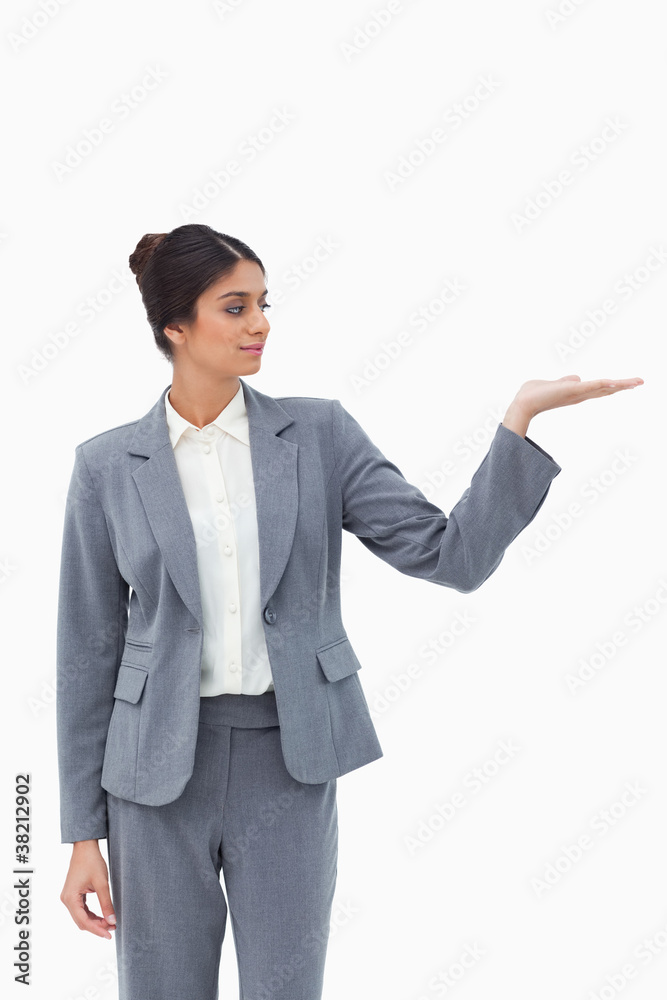 Saleswoman looking at what she is presenting in her palm Saleswoman looking at what she is presenting in her palm