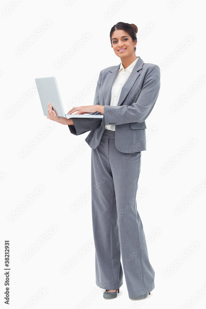 Smiling businesswoman using laptop while standing Smiling businesswoman using laptop while standing
