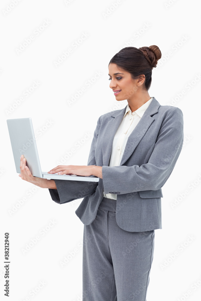 Smiling businesswoman using her laptop while standing Smiling businesswoman using her laptop while standing