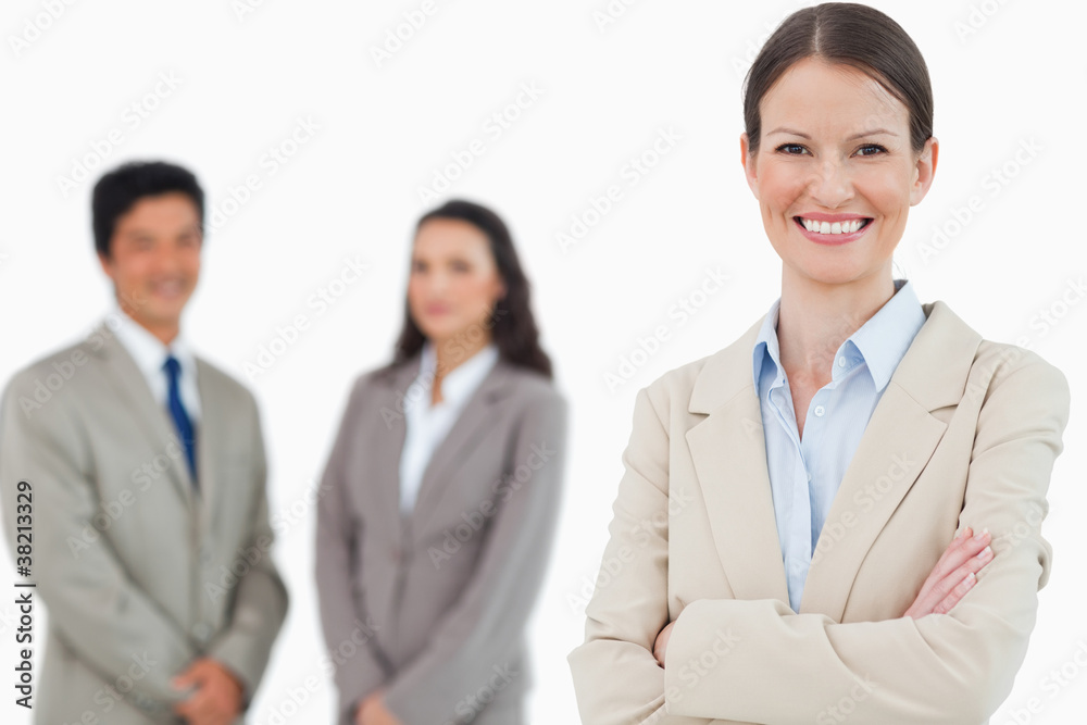 Smiling saleswoman with arms folded and associates behind her Smiling saleswoman with arms folded and associates behind her