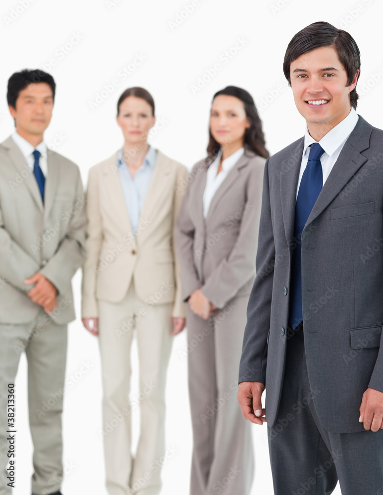 Smiling young salesman with his team behind him Smiling young salesman with his team behind him