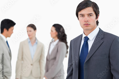 Young businessman with talking associates behind him