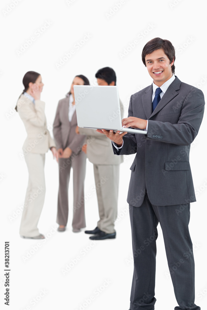 Smiling salesman with laptop and team behind him Smiling salesman with laptop and team behind him