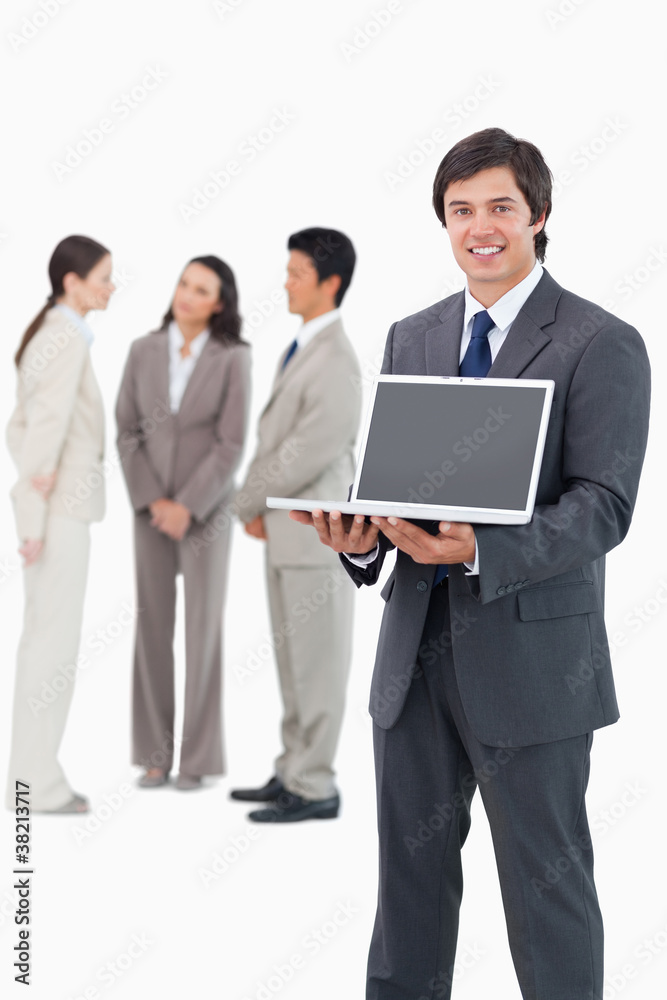 Smiling salesman showing laptop screen with team behind him Smiling salesman showing laptop screen with team behind him