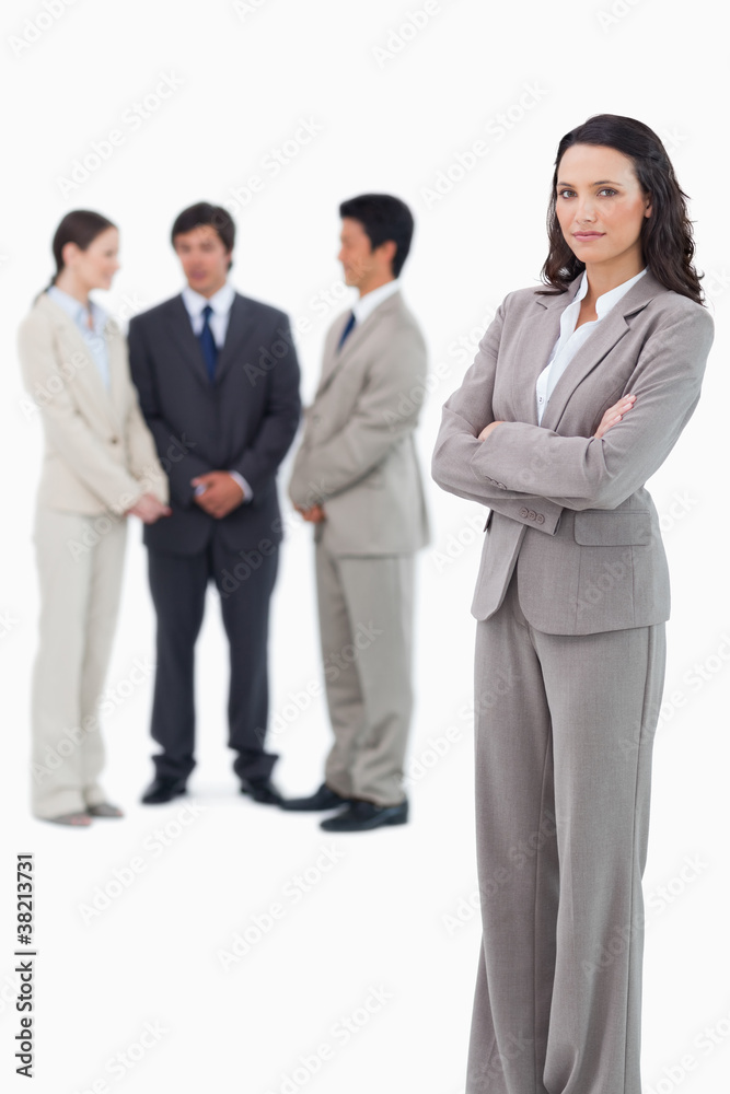 Serious saleswoman with arms crossed and team behind her Serious saleswoman with arms crossed and team behind her