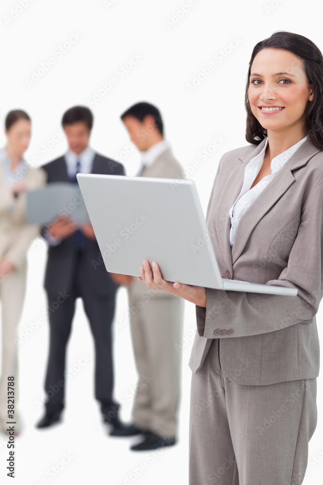 Smiling saleswoman with notebook and colleagues behind her Smiling saleswoman with notebook and colleagues behind her